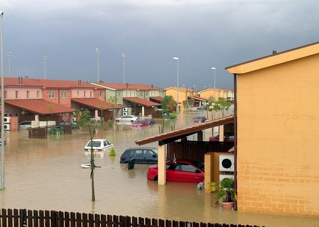 Calle inundada con una casa y varios coches