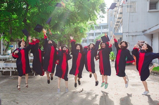 Plano general de alumnos graduados, saltando y tirando su bonete al aire