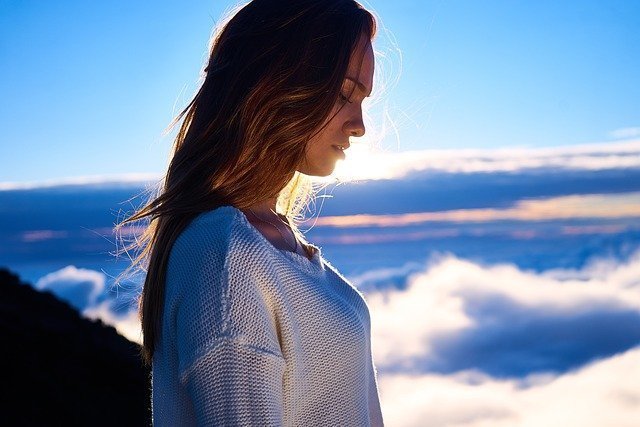 Mujer pensativa con fondo de cielo y nubes